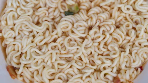 Closeup instant noodles texture, dry curled strands filling bowl, scattered seas Stock Footage 331838103