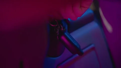 Closeup key in ignition console under magenta glow, hand turns to start engine Stock Footage 327354638