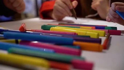 Closeup kid group drawing together on big paper with focus on colored markers Video stock 100908659
