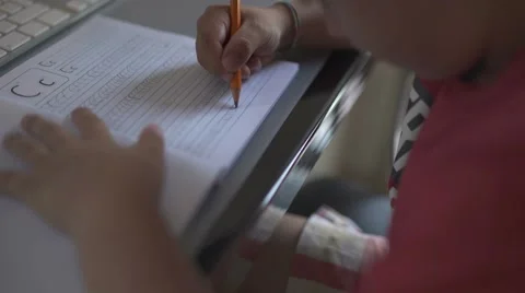 Closeup of kid practicing and learning to write letter C on an exercising book. Stock Footage