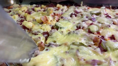 Closeup of a knife and fork slicing baked pizza with pineapple chunks, dice.. Stock Footage 346208717