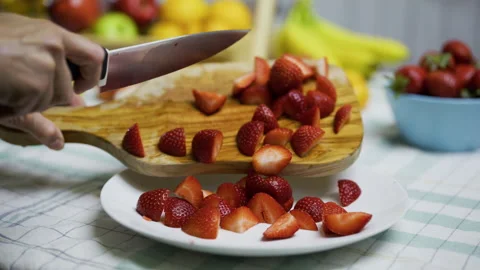Closeup of knife being used to scrape sliced strawberries onto plate Stock Footage 341183844