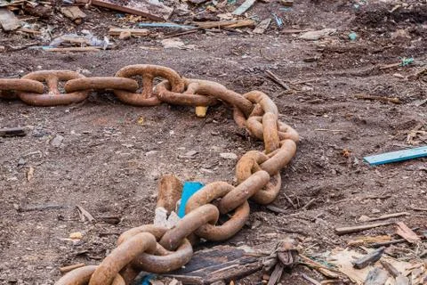 Closeup of large rusty chains laying on the ground Stock Photos