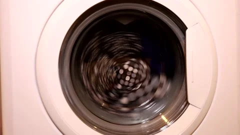 Closeup of laundry machine starts spinning clothes around. Washing machine. Stock Footage