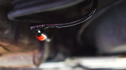 Closeup leaking fuel under car wires cables and falling drops chewed by rodents Stock Footage 161829517