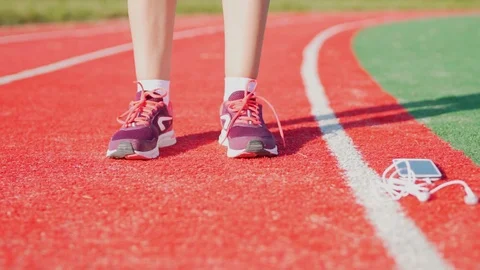 Closeup of legs of a female runner preparing for running, tying shoes, headphone Video stock 115193166