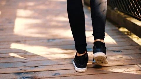 Closeup on legs walking slowmo across a wooden bridge on a sunny day Stock Footage 92458849