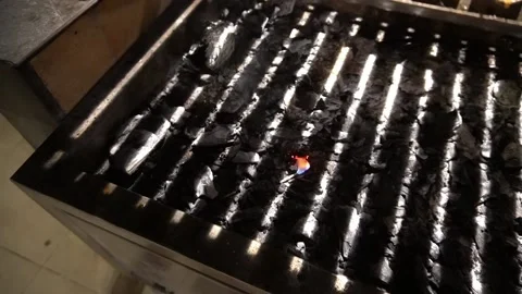 Closeup of a lighter with fire going out between coals in a grill at night Видео 181917836