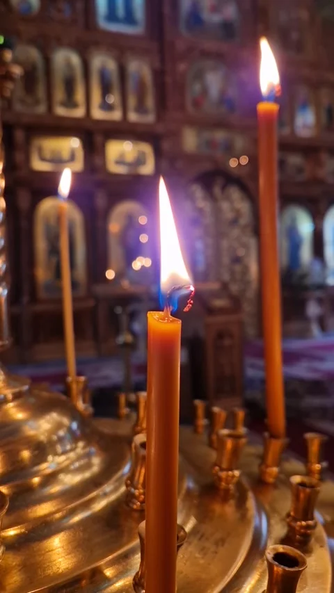Closeup of a lit candle on the candelabra inside a Christian Orthodox church. Th Stock Footage 303210784