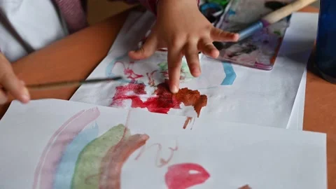 Closeup of a little child's hands drawing a rainbow on a sheet of paper Stock Footage 171381544