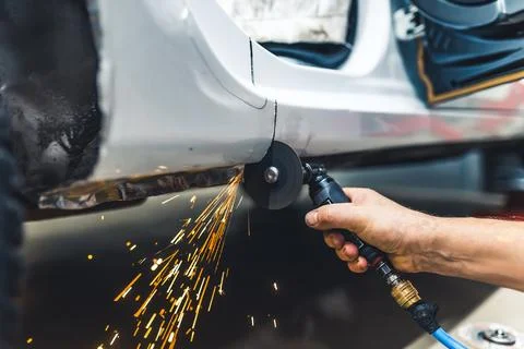 Closeup low angle view of caucasian hand holding working angle grinder and Stock Photos