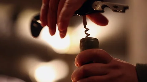 Closeup low angle view of corkscrew turning into wine bottle cork Stock Footage 342807466