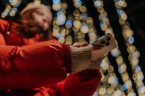 Closeup low-angle view of unrecognizable woman typing on mobile phone at dark Stock Photos