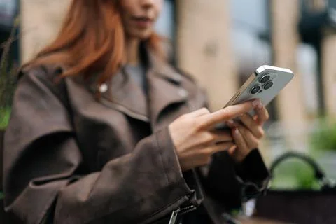 Closeup low-angle view of unrecognizable young woman using smartphone outdoors Stock Photos