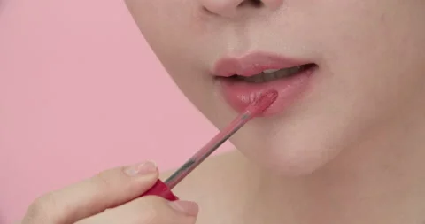 Closeup of lower half of Asian woman's face applying lipstick or gloss on lips. Stock Footage 206137979