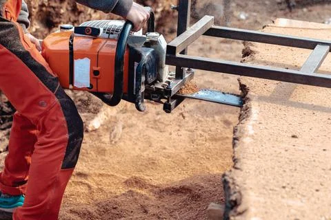 Closeup of lumberjack cutting tree trunk with giant chainsaw to make wooden p Stock Photos