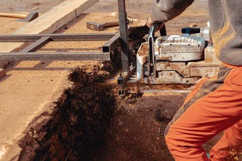 Closeup of lumberjack cutting tree trunk with giant chainsaw to make wooden p Stock Photos