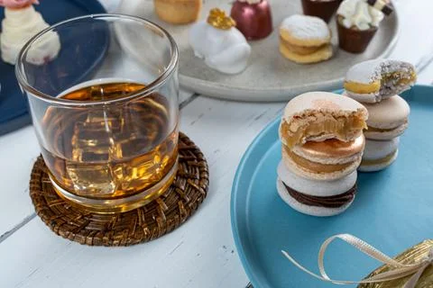Closeup of macarons stacked next to whiskey glass and fancy wedding candies. Stock Photos
