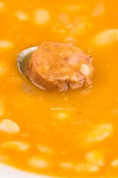 Closeup macro of cooked beans with sausage in the spoon Stock Photos