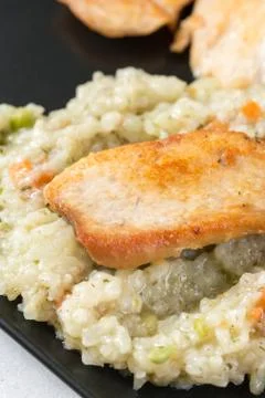 Closeup macro of fried chicken white meat with risotto in the black square pl Stock Photos
