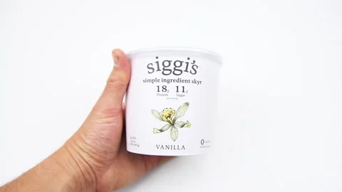 Closeup macro hand holding Siggi's zero fat yoghurt container white background Stock Footage 203853830