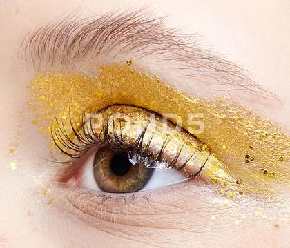 Closeup macro shot of human female eye with yellow smoky eyes beauty makeup. Stock Photos