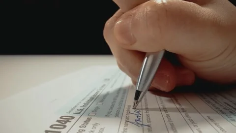 Closeup macro shot movement shot of corporate accountant lling 1040 tax form. Stock Footage 243363436