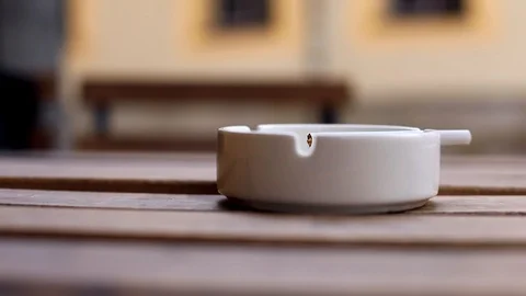 Closeup macro view of cigarette in white ashtray on wooden table on blur backgro 스톡 동영상 118506509