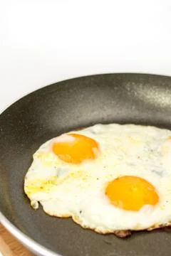 Closeup macro view of fried eggs in teflon frying pan Stock Photos