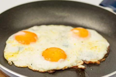 Closeup macro view of fried eggs in teflon frying pan Foto stock