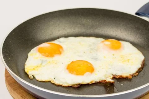 Closeup macro view of fried eggs in teflon frying pan Stock Photos