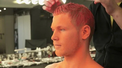 Closeup of makeup master covering man's hair with bright oragne color Stock Footage 73537644