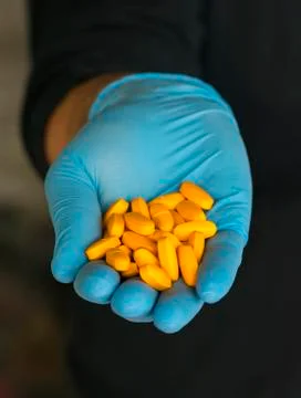 Closeup of male hand with blue glove and  pills capsules Stock Photos