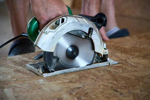Closeup of a male hand using an electric circular saw to cut a sheet of wood  Stock Photos