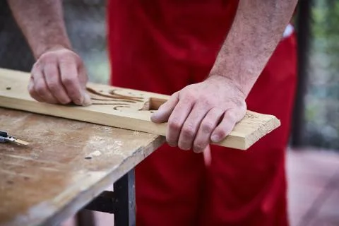 Closeup of male hands carpenter using sandpaper to sand wooden detail. Stock Photos