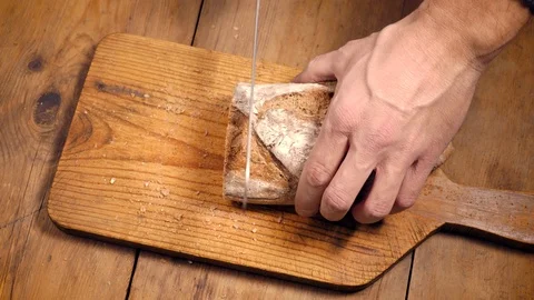 Closeup of male hands cutting bread slices on a wooden board Stock Footage 121129919