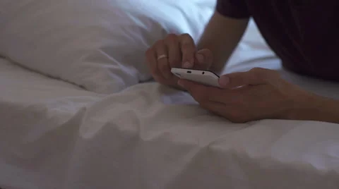 Closeup of male hands using smart phone with blank screen while lying in bed at Stock Footage 67750337