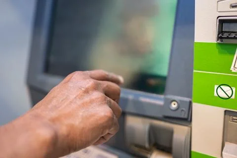 Closeup of male hands using smart phone while typing on ATM, bank machine. Ma Stock Photos