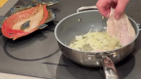 Closeup of man addiing fish filets to a pan of onions sizzling in butter Video stock 273176552