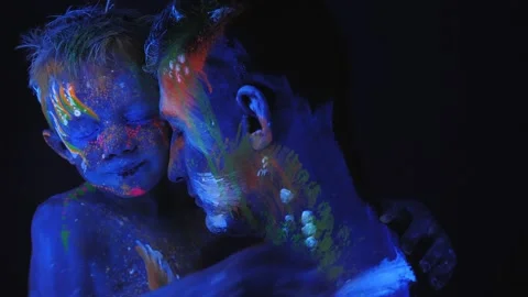 Closeup of a man with a child with neon makeup that is made of fluorescent paint Stock Footage 130254164