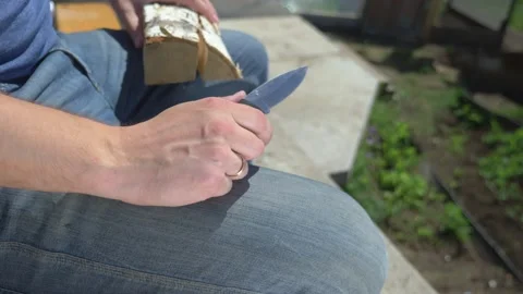 Closeup. man cuts out patterns with a knife on a wooden board, outdoors Stock Footage 133216660