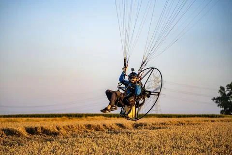 Closeup of a man doing a paramotor flight paragliding over the wheat fields Stock Photos