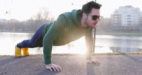 Closeup of man doing push-ups exercise in park during sunset Stock Footage 235685079