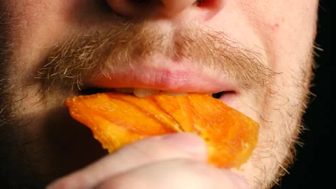 Closeup of man eating persimmon, Individual enjoying dried persimmon with Stock Footage 337546944