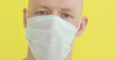 Closeup man face in medical mask in coronavirus pandemic on yellow background. Stock Footage 131234945