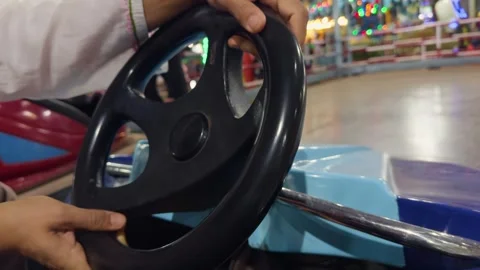 Closeup man hand on a bumper car steering wheel with colorful cars in the b.. Stock Footage 264147888