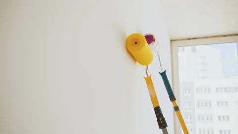 Closeup man hand holding paint roller on wall. Unknown woman hand leading roller Stock Footage 232128070