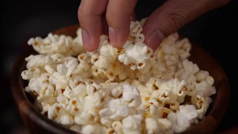 Closeup man hand taking popcorn from wood bowl. Eating pop corn at home Stock-Footage 143753064