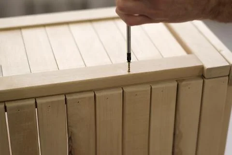 Closeup man hand using manual screwdriver and screwing screw in board Foto stock