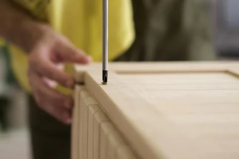 Closeup man hand using manual screwdriver and screwing screw in board Foto stock